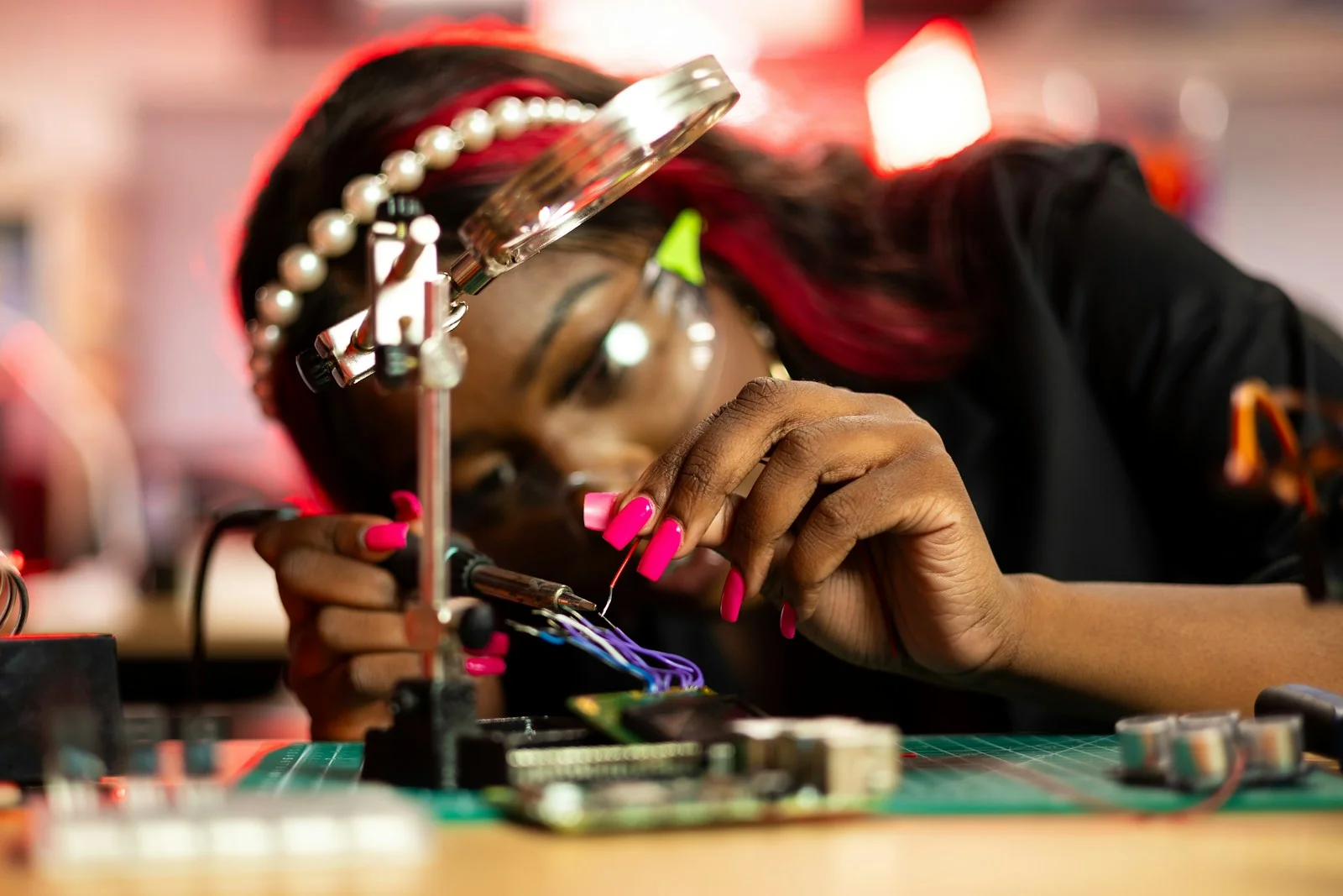 Hands-on electronics work using a magnifying glass and circuit board